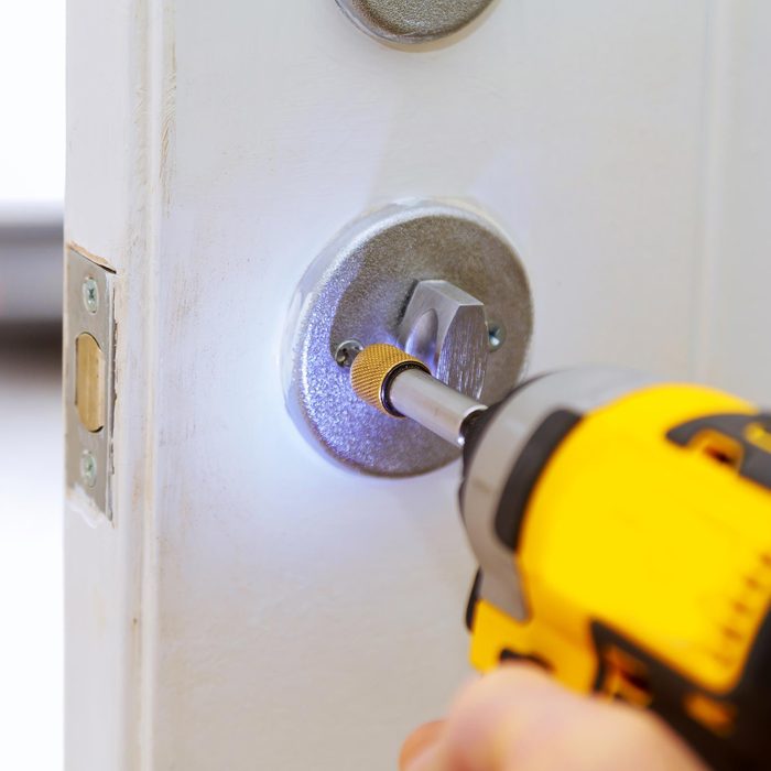 Professional Locksmith Installing Or Repairing A New Deadbolt Lock on a House Exterior Door With The Inside Internal Parts Of The Lock Visible