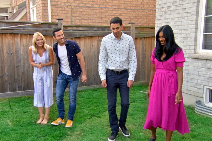four people standing in a backyard. Two have their eyes closed and are waiting for something unseen to be revealed to them