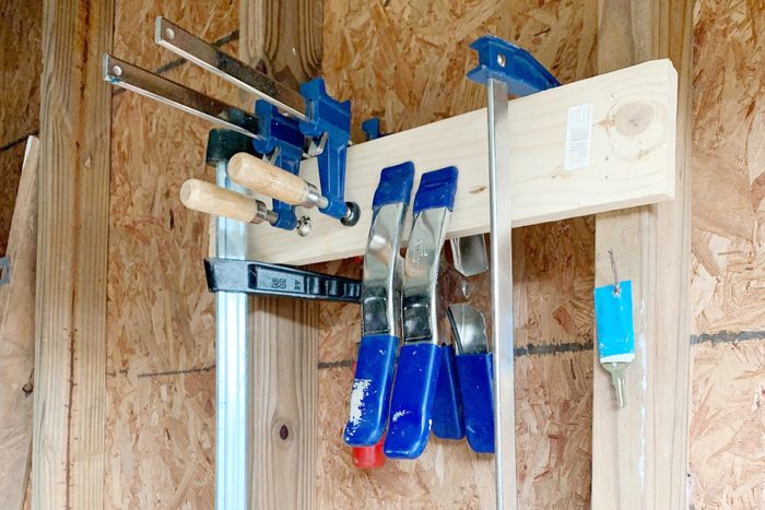 homemade clamp storage made put of wood with various clamps hanging from it