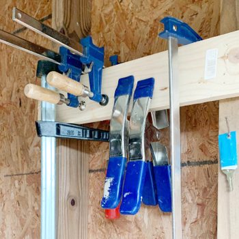 homemade clamp storage made put of wood with various clamps hanging from it