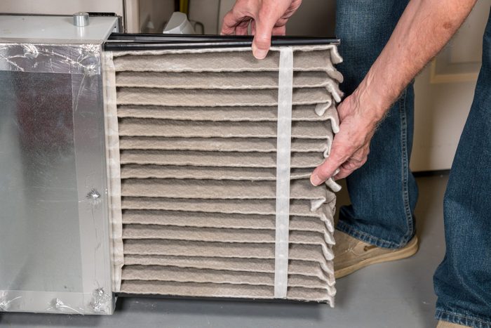 Senior man changing a dirty air filter in a HVAC Furnace