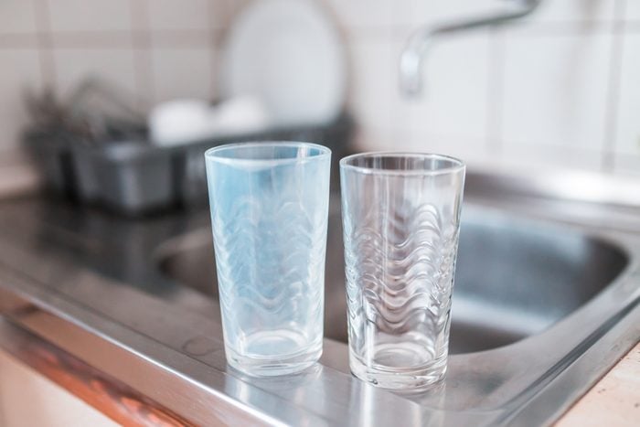 Dirty and clean glass cups on a kitchen sink. Broken dishwasher