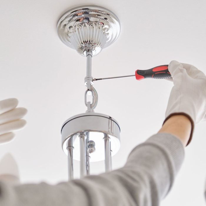 Hands Of Electrician installing a chandelier with professional tools