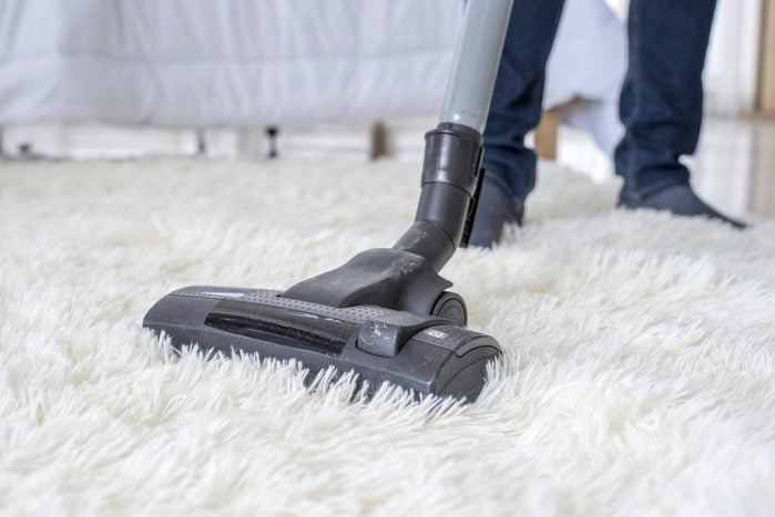 Vacuum cleaner cleaning a white fuzzy carpet
