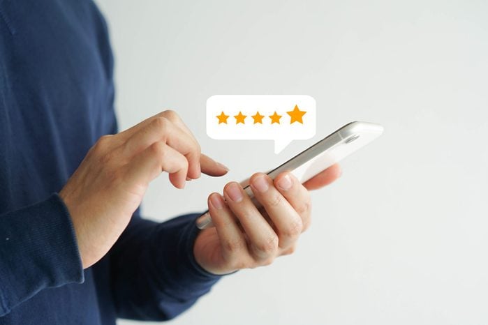 close up on customer man hand pressing on smartphone screen with five star rating feedback icon and press level good rank for giving best score point to review the service , technology business concept