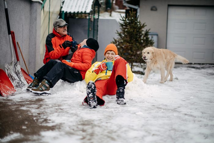 Multi-generation family cleaning snow from back yard