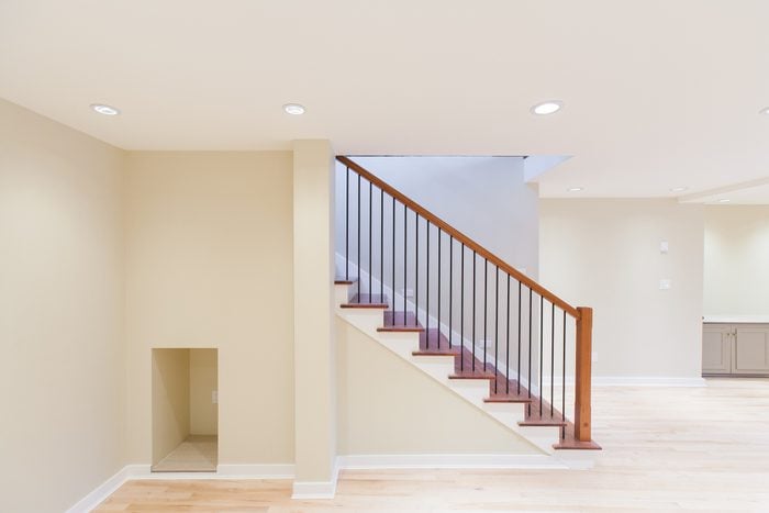 a bright finished basement with light colored luxury vinyl flooring, and a wooden staircase