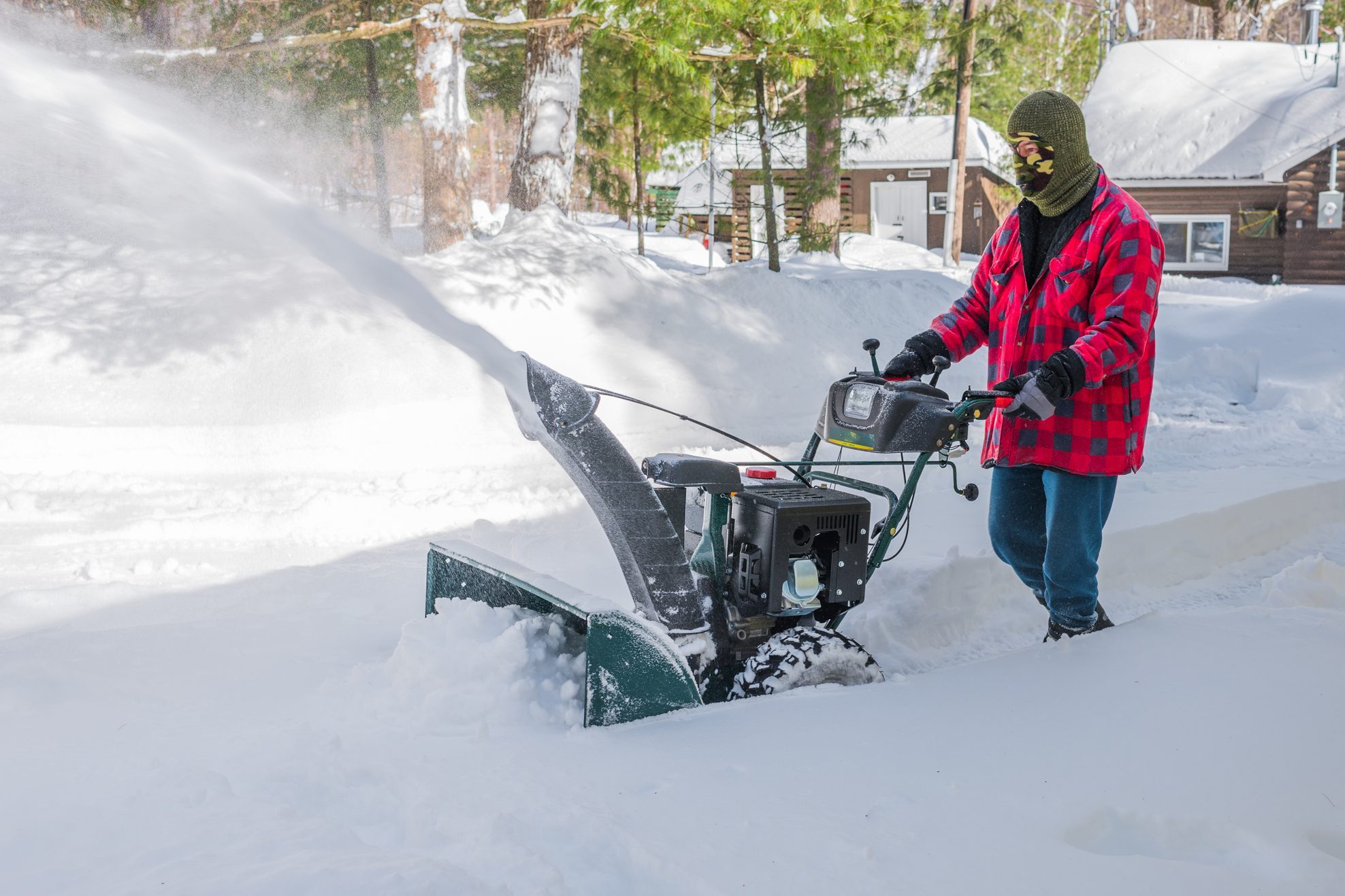 Canadian Man operates snow thrower on winter day in Canada.