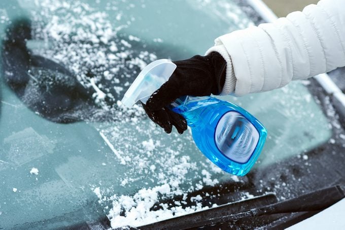 Ice scraping with defrost spray on car windshield