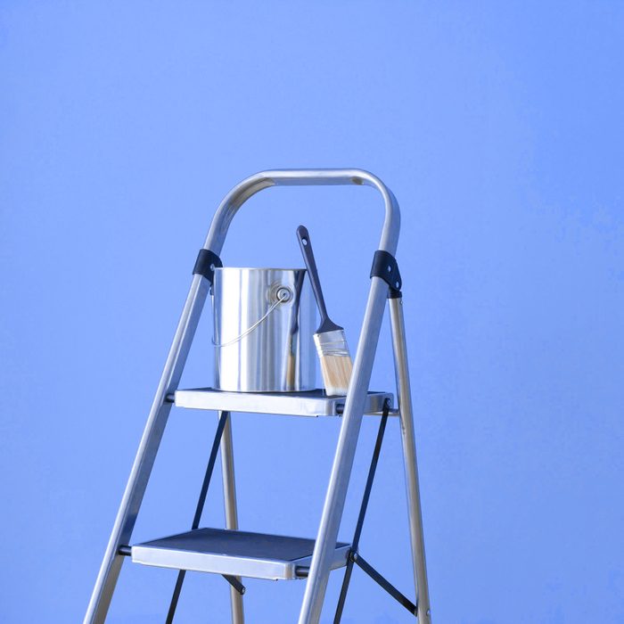 Preparing to paint a Blue wall with a painting ladder metal paint bucket and a paintbrush