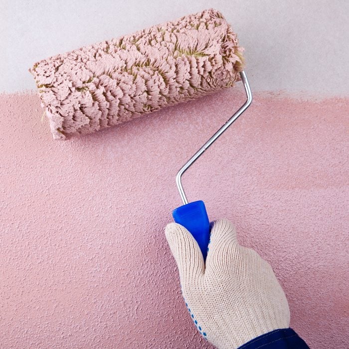 House Painter Using Paint Roller to paint a pink wall