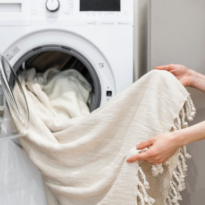 Woman Unloading Laundry From White Washing Machine