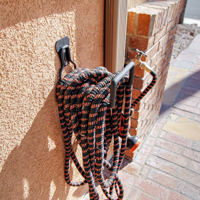 Expandable Garden Hose on a holder outside of a house