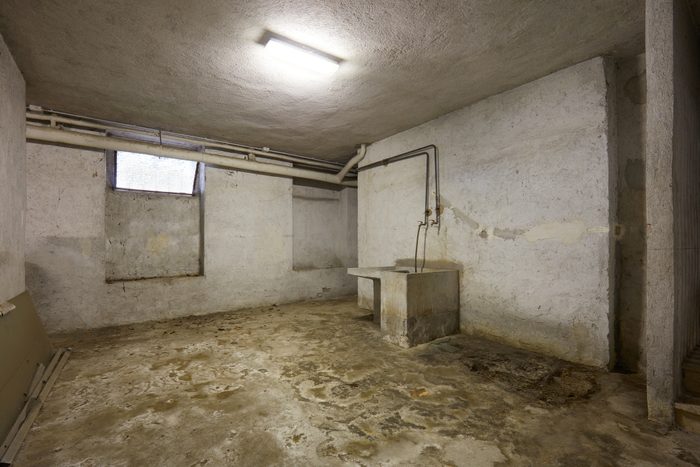 Basement with sink and dirty floor in old house interior