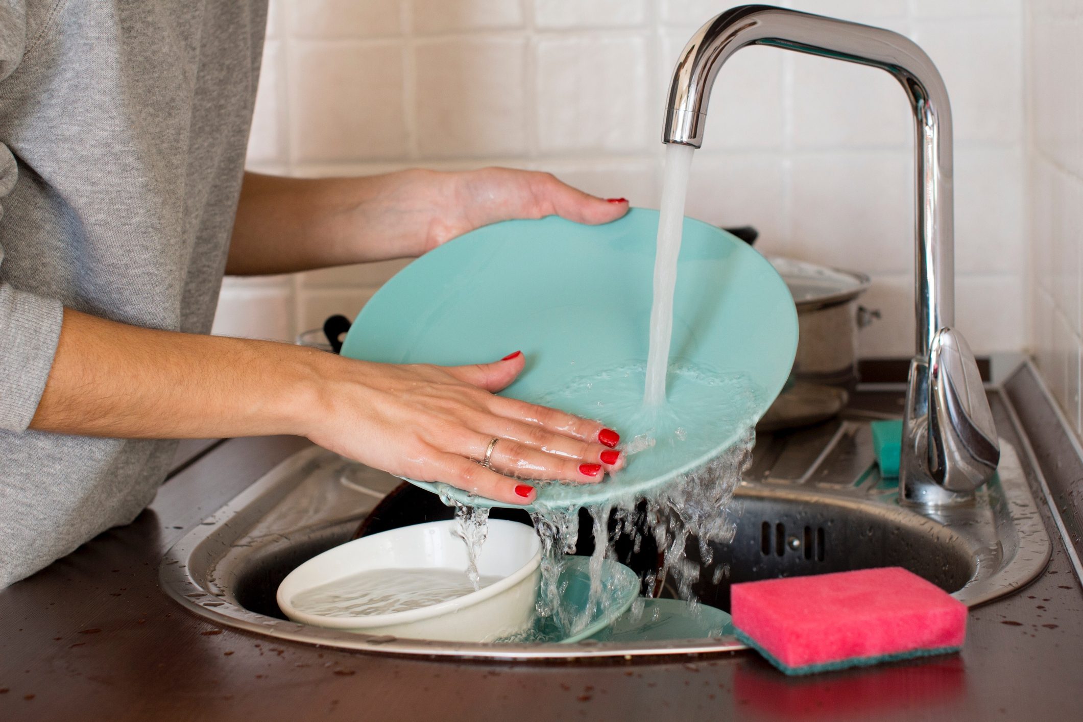 Midsection Of Woman Cleaning Plates In Kitchen At Home
