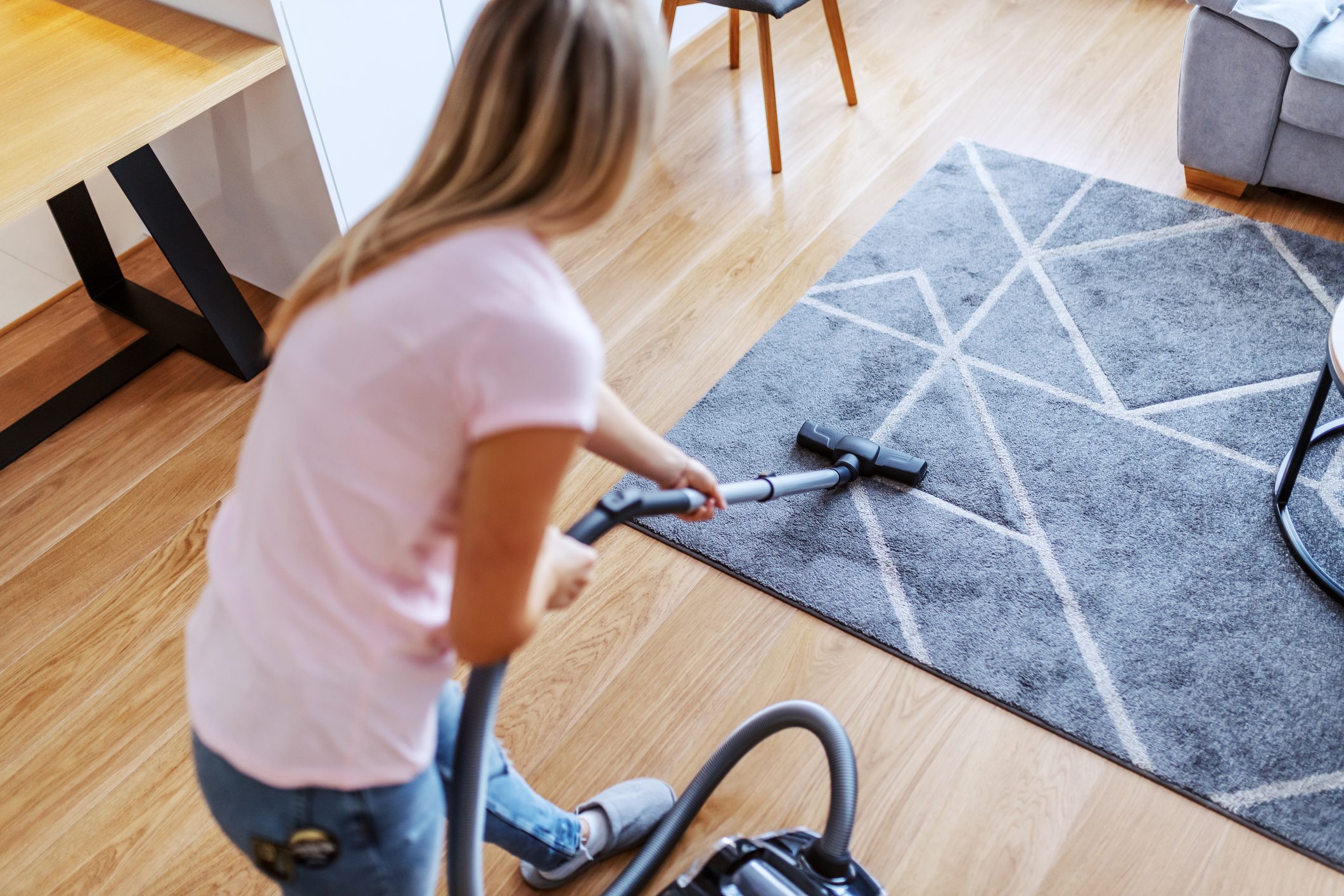 Rear view of woman vacuuming in apartment living room