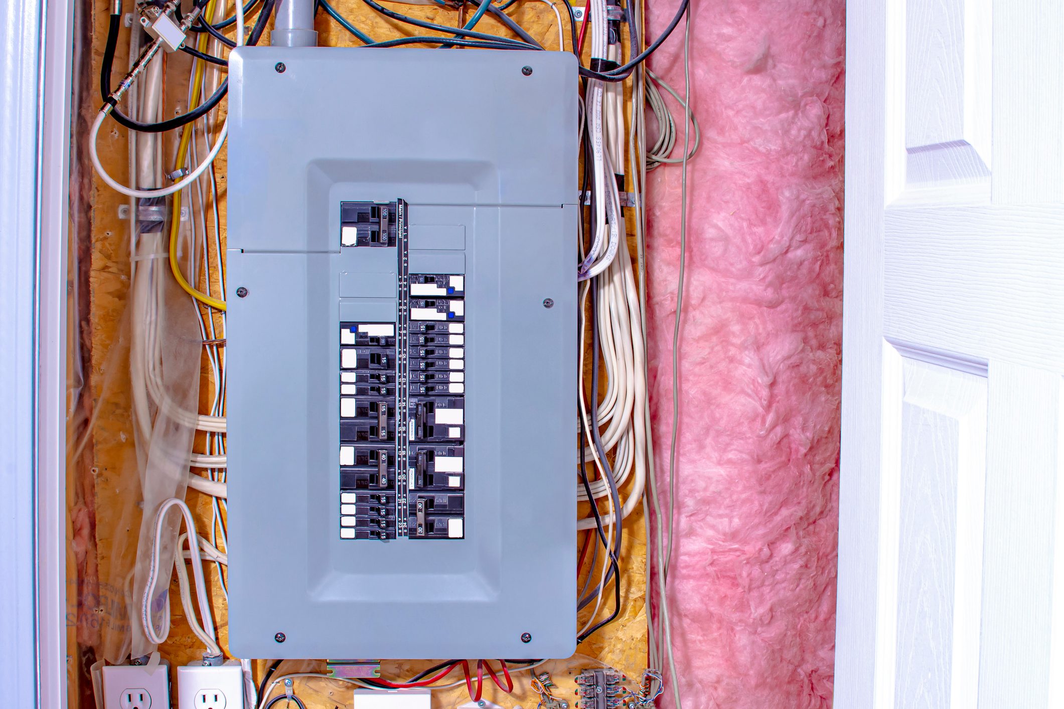 breaker box on a wall with wires and insulation