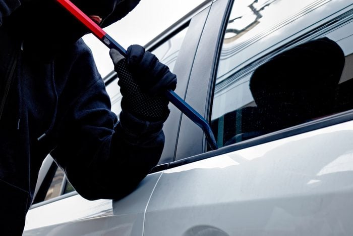 Masked burglar trying to break into a car