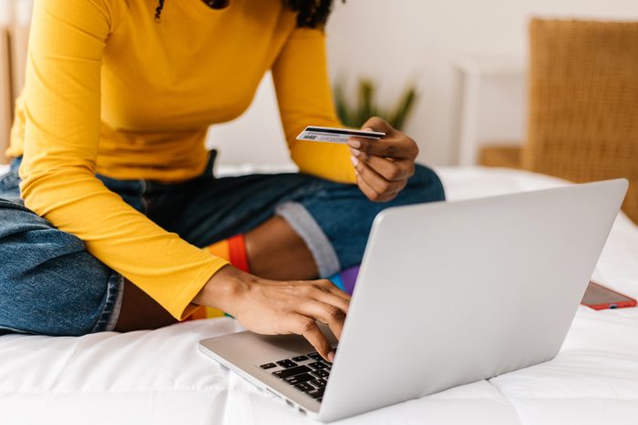Close up woman hands using credit card to buy online on laptop