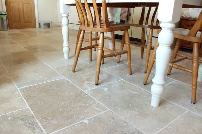 Image of filled travertine tile floor, kitchen table and chairs