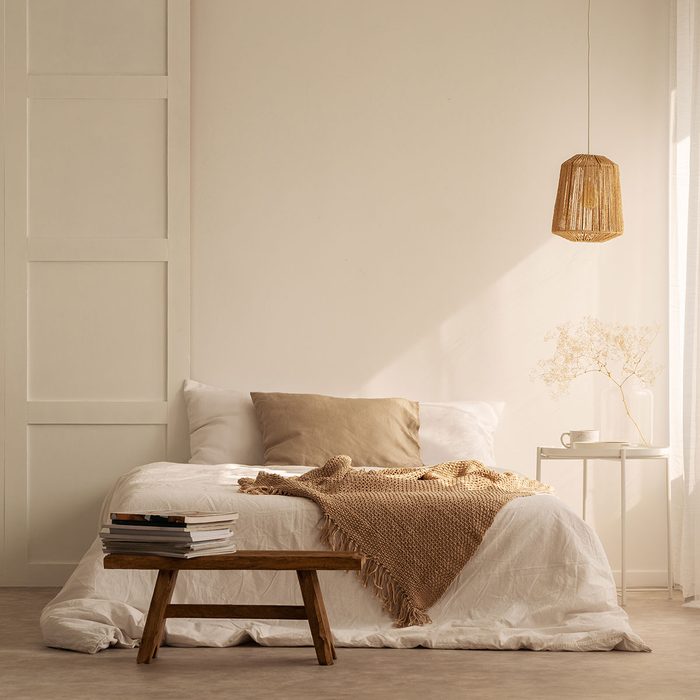 Beige Bedroom with blankets on double bed in stylish wabi sabi bedroom