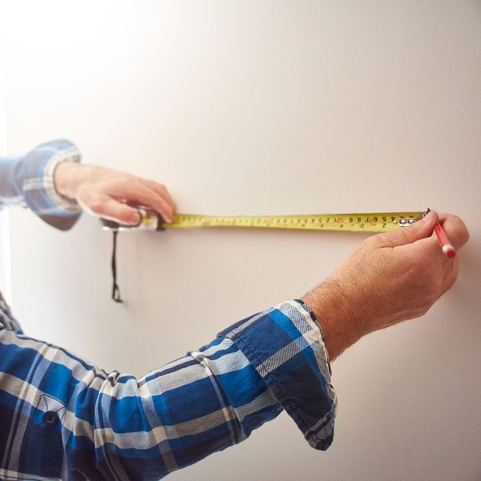 Man Marks out points on a wall with a tape measure