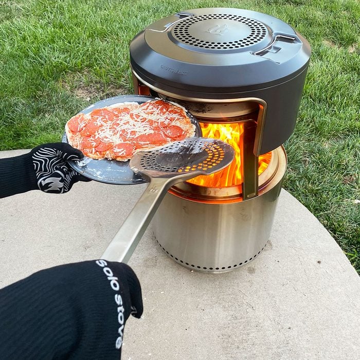 Cooking pizza in open fire grill outside in backyard