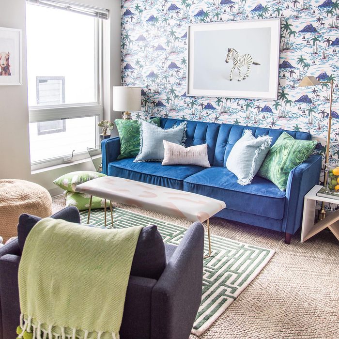 apartment living room with blue couch and removable bird wallpaper