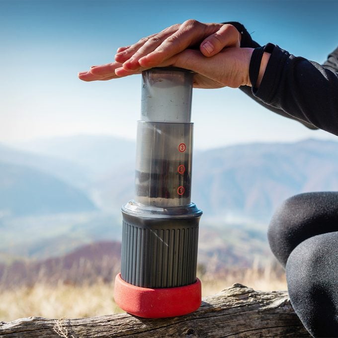 hand using an aero press coffee maker outside on a hike