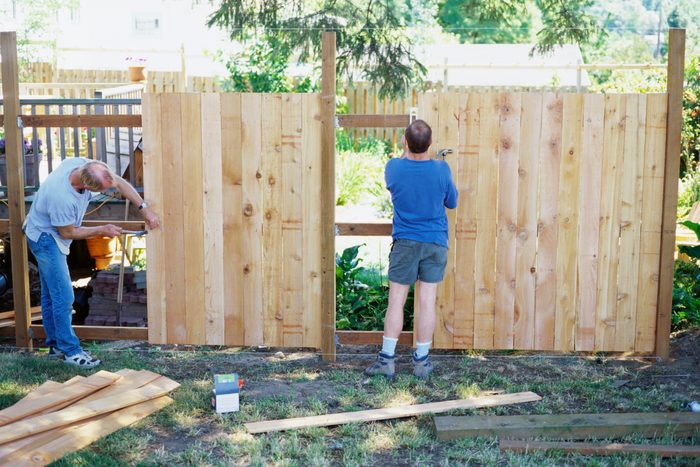 two men installing a wooden fence