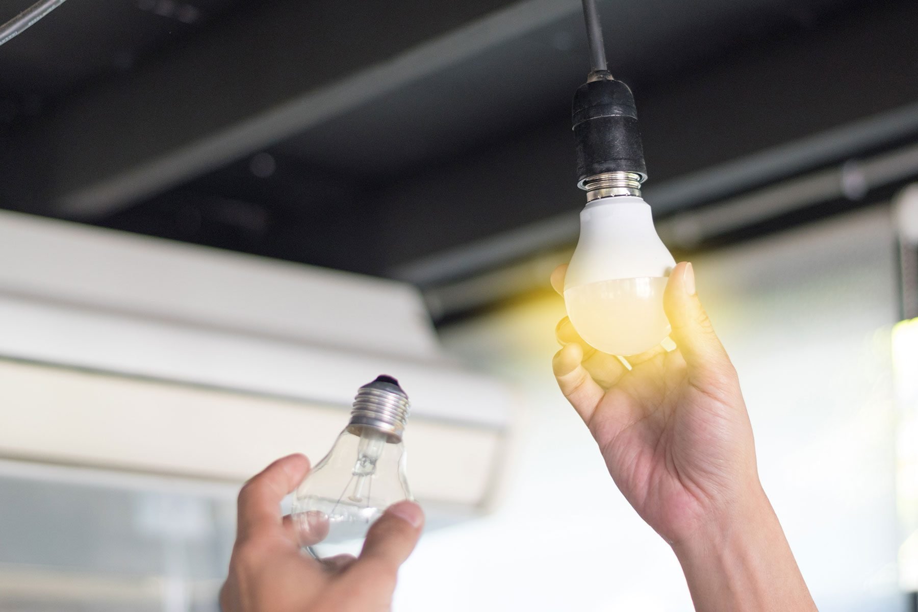 Man changes fluorescent bulbs with new LED light bulb