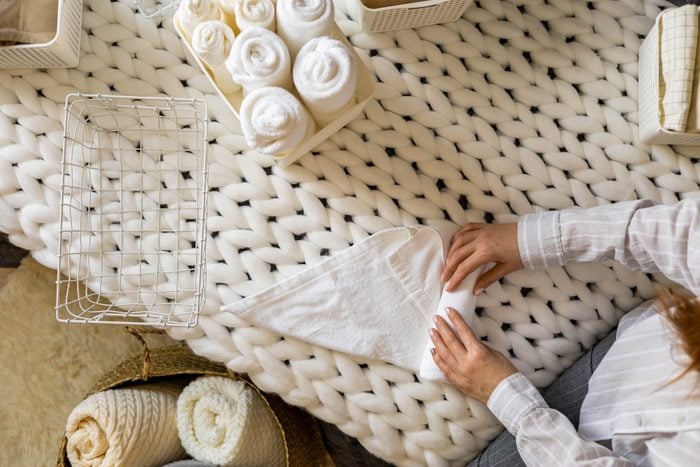 Top view female hands neatly folded white clean towels in case box use Marie Kondo organizing method