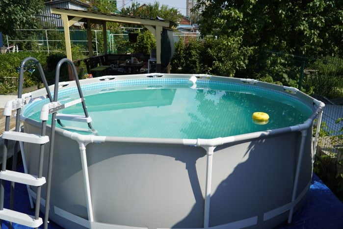 Round above ground pool with water in the garden