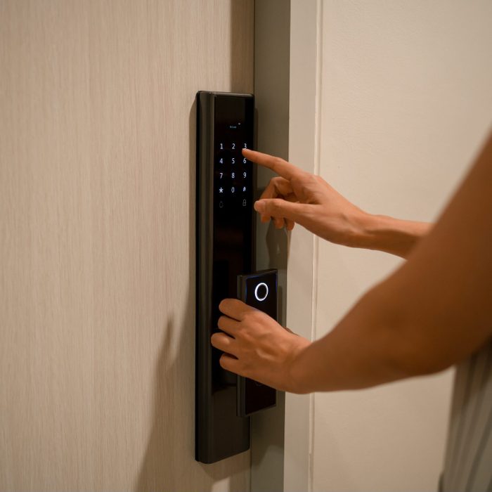 Woman Pressing down a password on electronic access control to unlock a door room at home