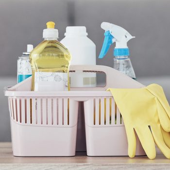 Cleaning container, spray bottle or rubber gloves on table in house, home or hotel living room for bacteria protection cleaner service. Zoom, housekeeping or healthcare hygiene product in maintenance