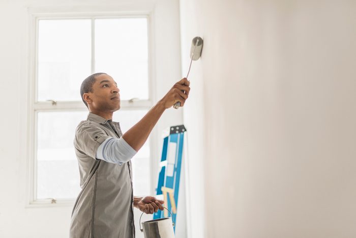 Black man painting wall of home