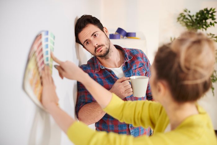 Young couple in new home look over paint swatches on the wall