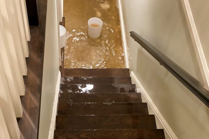 flood water flowing down staircase into house basement