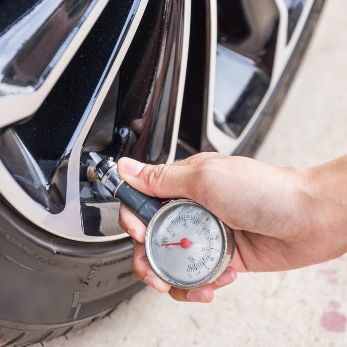 Closeup Of Hand holding pressure gauge for car tyre