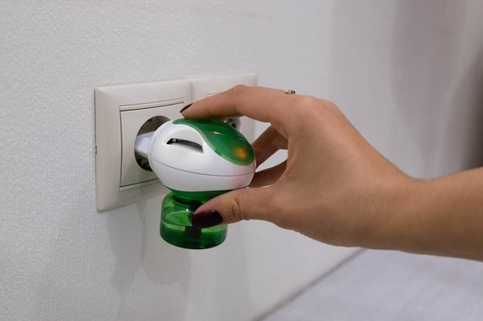 Electric mosquito trap device. insect killer. A woman puts a raptor from an insect into an electrical outlet