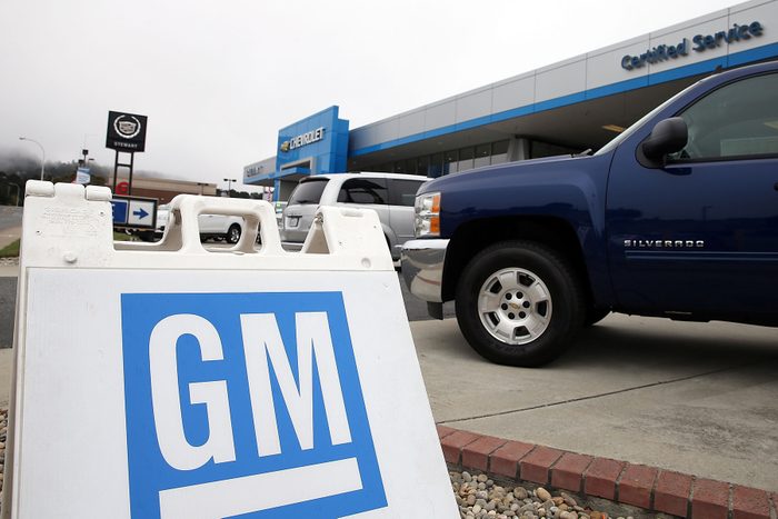 GM Sign Logo sits in front of A brand new Chevrolet truck is displayed at a Chevrolet dealership