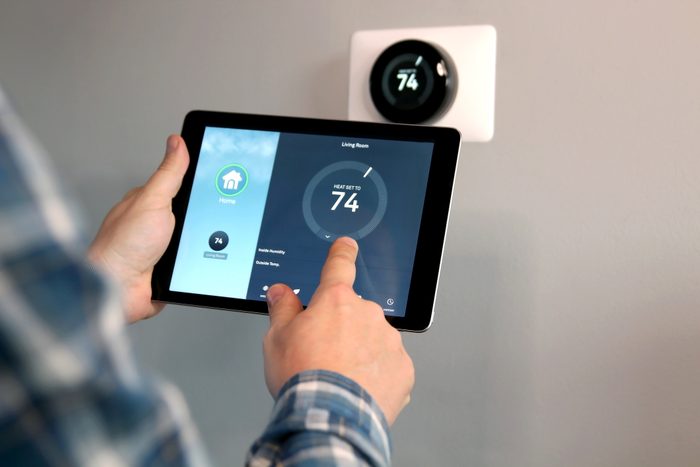 Man is Adjusting a temperature using a tablet with smart home app in modern living room