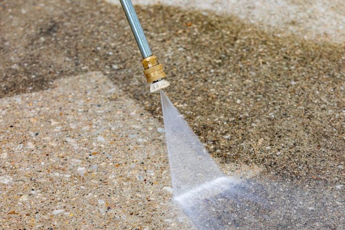 Pressure washing dirty concrete driveway. Home cleaning, maintenance and household chores concept