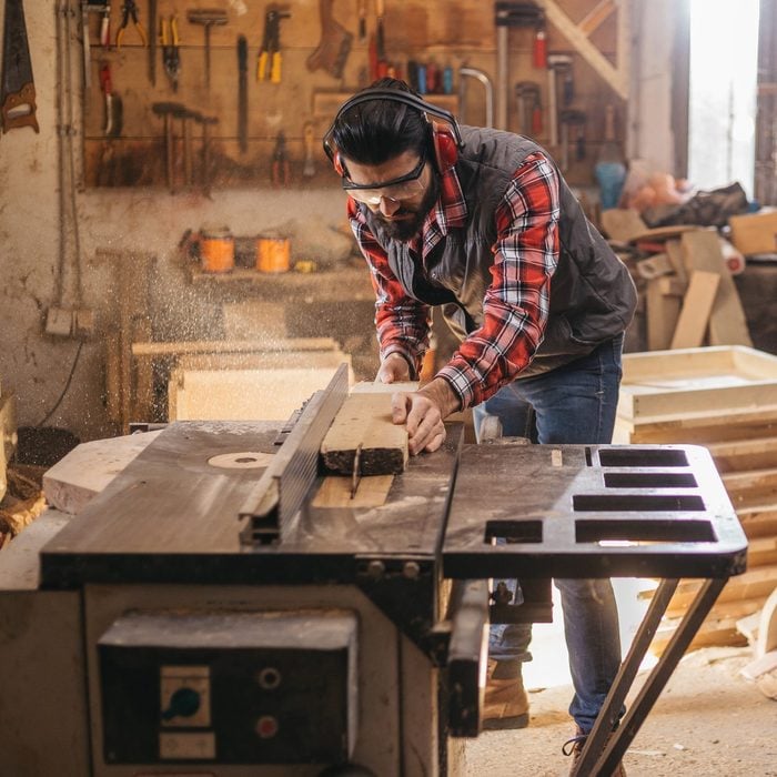 Carpenter cutting plank with a table saw