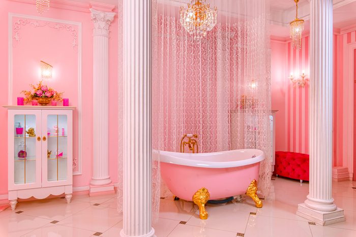 Spacious Pink Bathroom with chandeliers, draperies, columns and a gold and pink clawfoot bathtub
