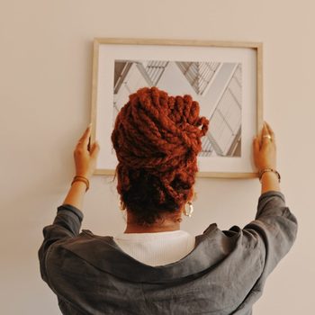 Shot of a unrecognizable female hanging a painting at home