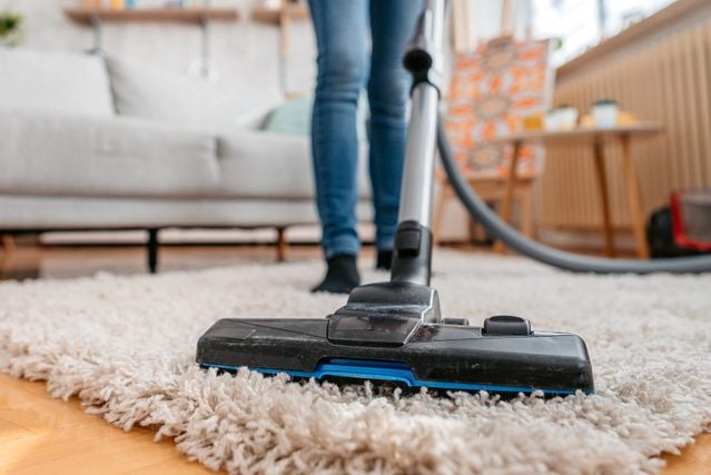 Young Woman Vacuuming Her Apartment