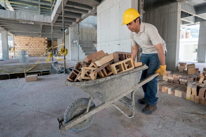 Construction worker carrying bricks on a wheelbarrow