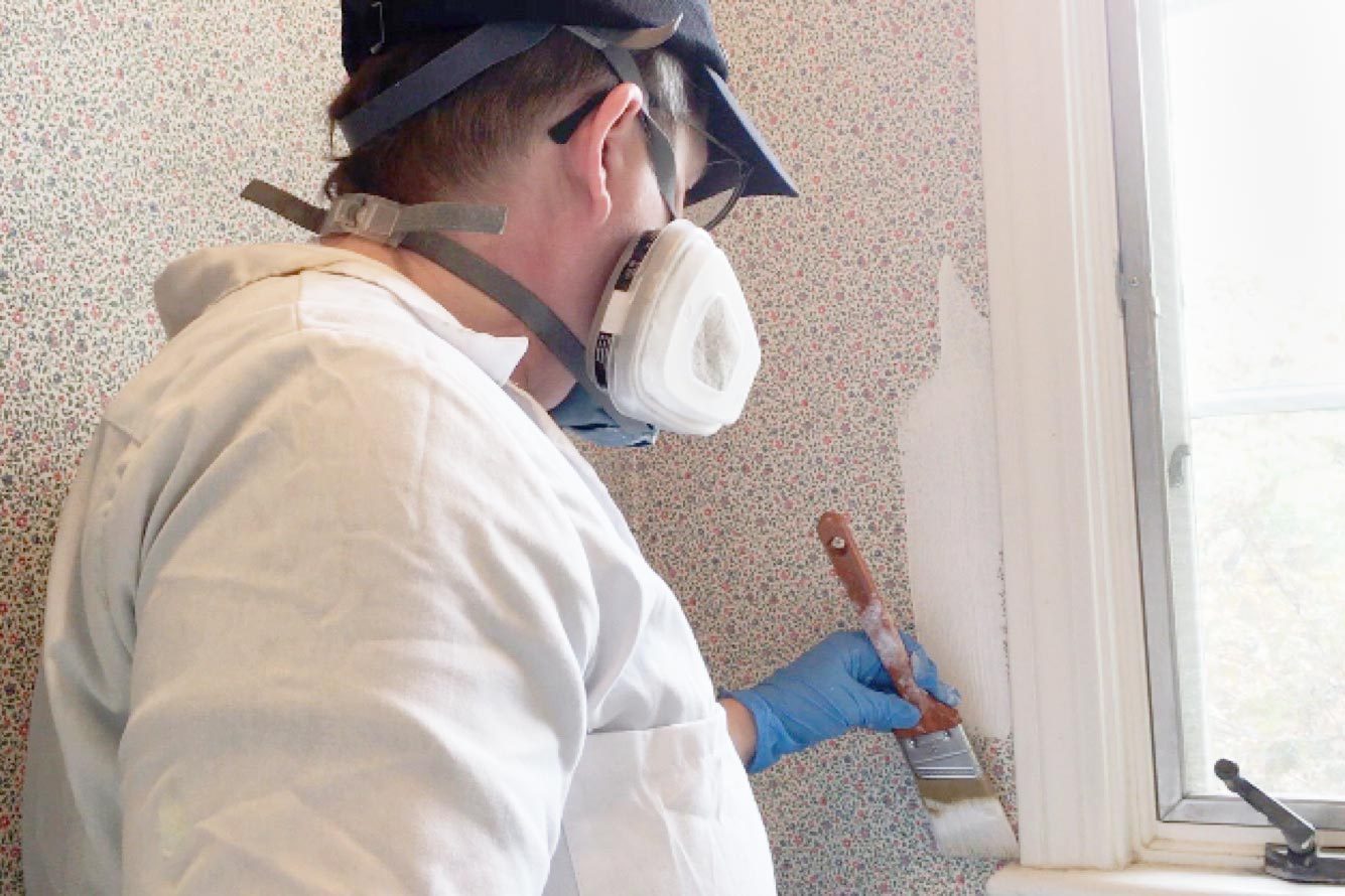 painting on primer on wallpaper with brush