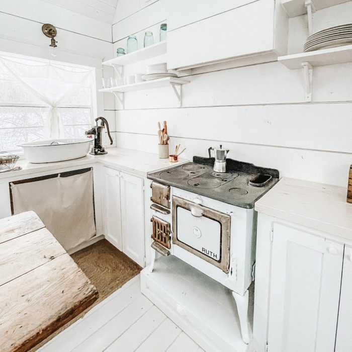 tiny home she shed with a white farmhouse style kitchen and stove
